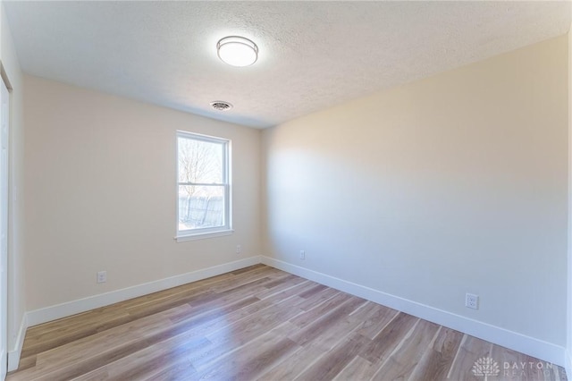 unfurnished room featuring a textured ceiling and light hardwood / wood-style flooring