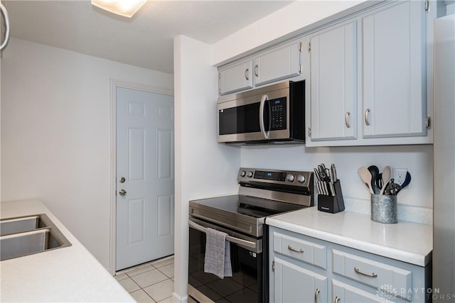 kitchen featuring stainless steel appliances, gray cabinets, sink, and light tile patterned floors