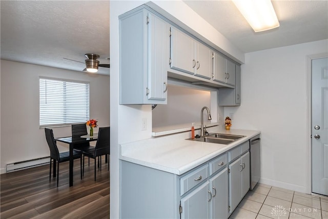 kitchen featuring sink, ceiling fan, a baseboard heating unit, a textured ceiling, and stainless steel dishwasher