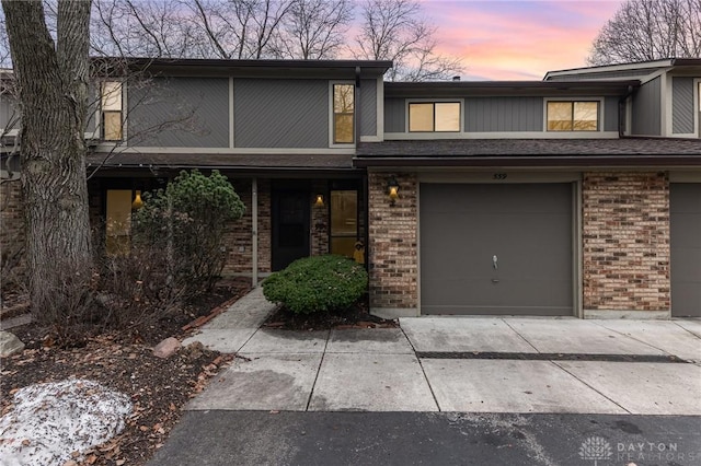 multi unit property featuring driveway, an attached garage, and brick siding