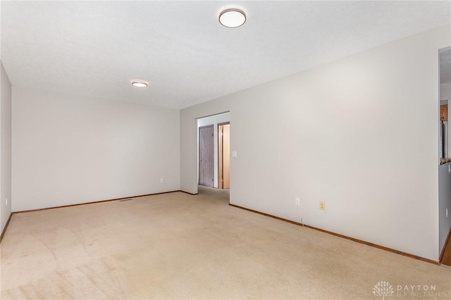 spare room featuring baseboards and light colored carpet