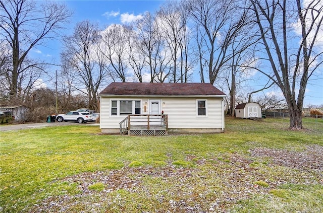 view of front of home with a storage unit, a front lawn, an outdoor structure, and fence