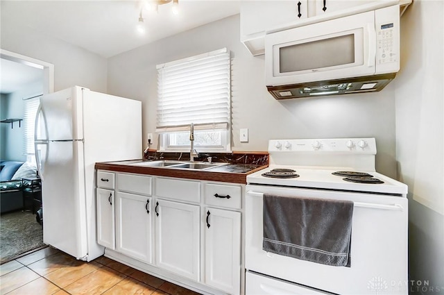 kitchen with white appliances, white cabinets, a sink, and light tile patterned flooring