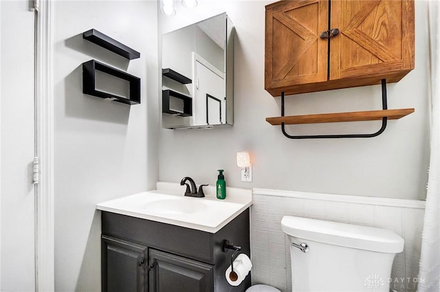 bathroom with toilet, vanity, and wainscoting