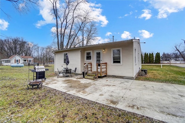 back of property with a yard, a fire pit, cooling unit, and a patio