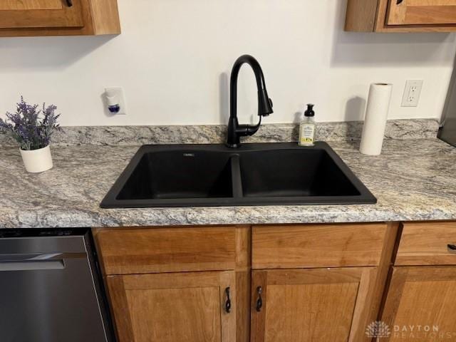 kitchen with light stone counters, stainless steel dishwasher, and sink