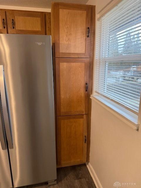 kitchen with dark wood-type flooring, stainless steel fridge, and a healthy amount of sunlight