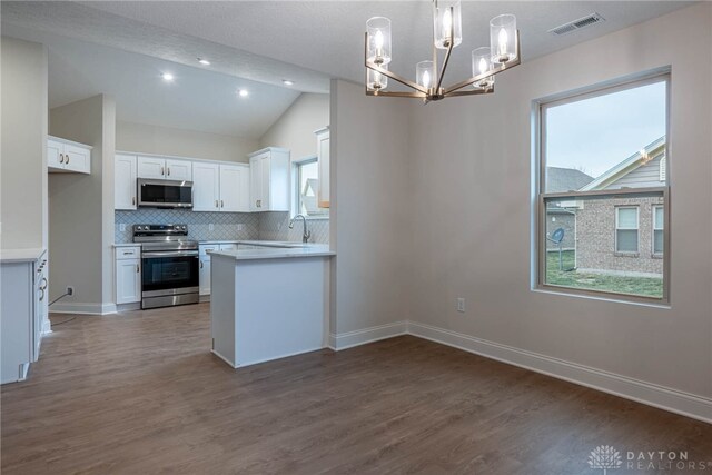 2220 Tandem Dr, Xenia, OH 45385 - kitchen featuring vaulted ceiling, appliances with stainless steel finishes, pendant lighting, decorative backsplash, and white cabinets