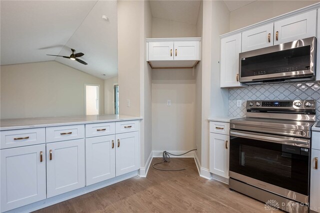 2220 Tandem Dr, Xenia, OH 45385 - kitchen with lofted ceiling, white cabinetry, appliances with stainless steel finishes, light hardwood / wood-style floors, and backsplash
