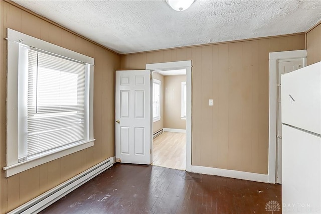 empty room featuring dark wood-type flooring, a baseboard radiator, and a textured ceiling