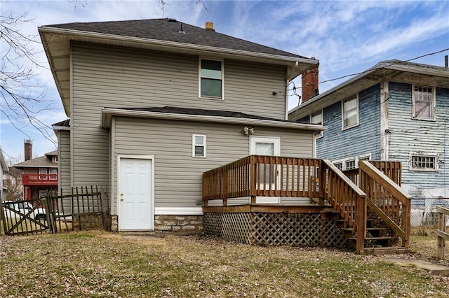 rear view of property featuring a deck and a lawn