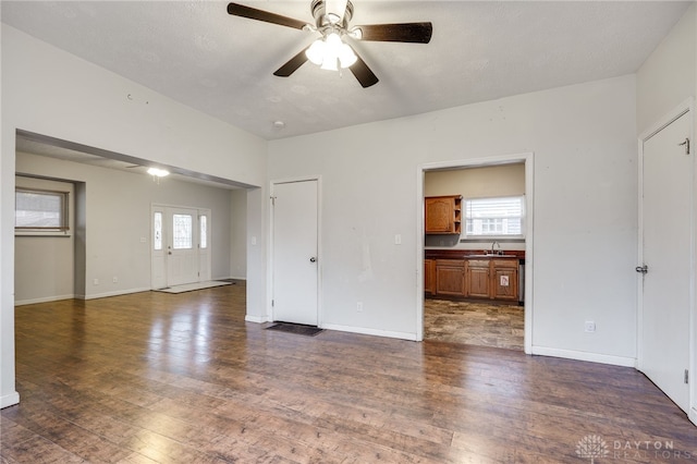 unfurnished living room featuring a healthy amount of sunlight, sink, and dark hardwood / wood-style floors