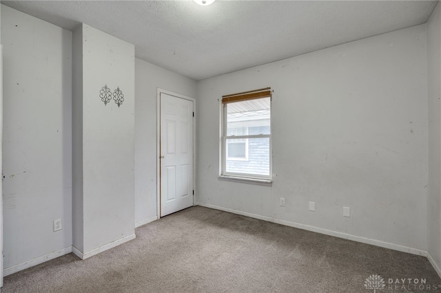 unfurnished room featuring light colored carpet and a textured ceiling