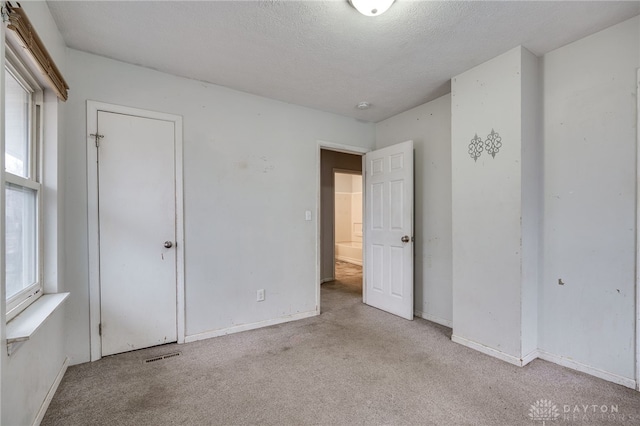 unfurnished bedroom with light colored carpet and a textured ceiling