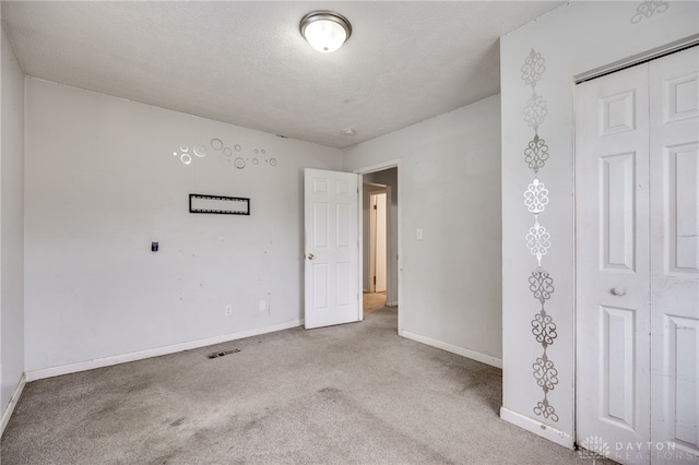 carpeted empty room featuring a textured ceiling