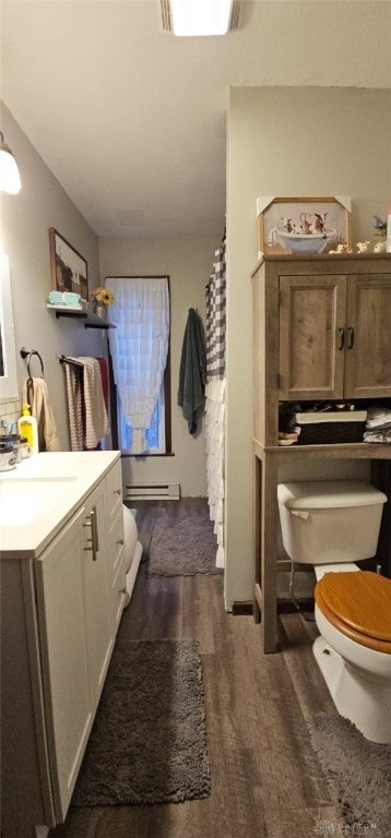 bathroom with toilet, vanity, wood finished floors, and a baseboard radiator