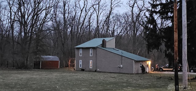 view of home's exterior with a chimney, a shed, and an outbuilding
