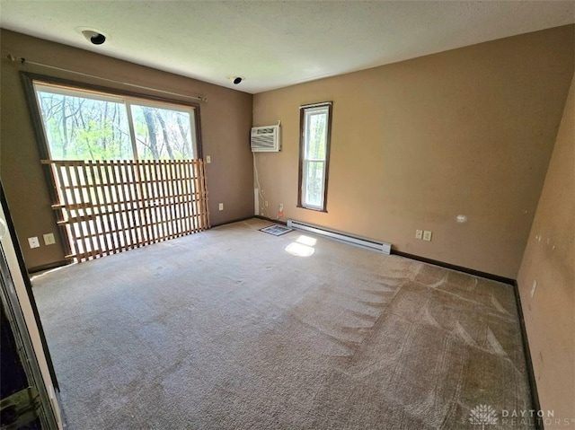 spare room with a healthy amount of sunlight, a baseboard heating unit, carpet floors, and an AC wall unit