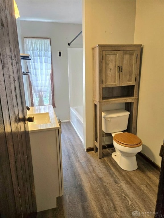full bath with wood finished floors, toilet, vanity, baseboards, and tub / shower combination