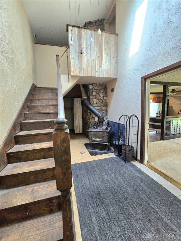 staircase featuring a wood stove and a textured wall