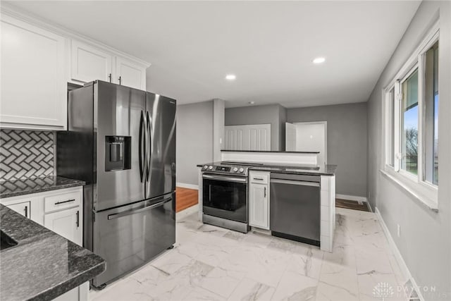 kitchen featuring white cabinetry, appliances with stainless steel finishes, dark stone counters, and decorative backsplash