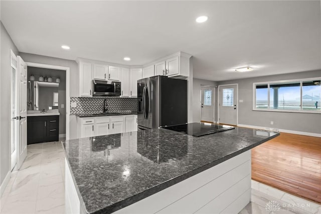 kitchen with decorative backsplash, a spacious island, white cabinets, and black appliances