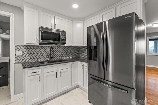 kitchen with white cabinetry, appliances with stainless steel finishes, sink, and dark stone countertops