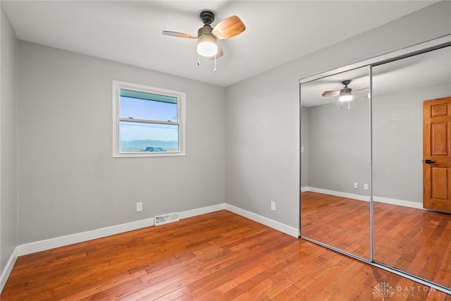 unfurnished bedroom with hardwood / wood-style flooring, a closet, and ceiling fan