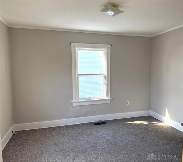 carpeted spare room with visible vents, baseboards, and ornamental molding