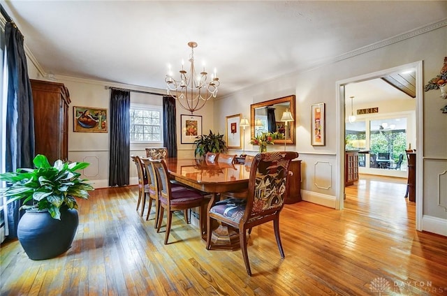 dining space featuring light hardwood / wood-style floors, a chandelier, and ornamental molding