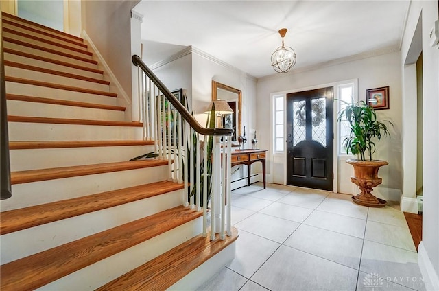 foyer entrance featuring baseboard heating, light tile patterned floors, crown molding, and a notable chandelier