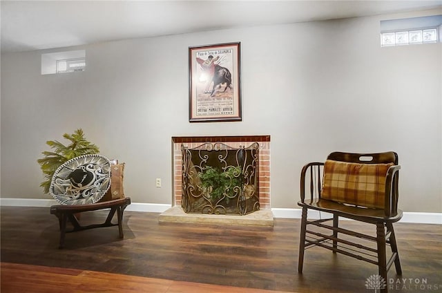 living area with a brick fireplace and dark hardwood / wood-style flooring