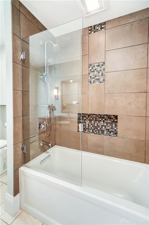 bathroom featuring tile patterned floors, toilet, and shower / bath combination with glass door