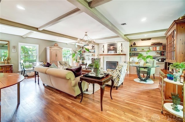 living room with light wood-type flooring, a chandelier, and beamed ceiling