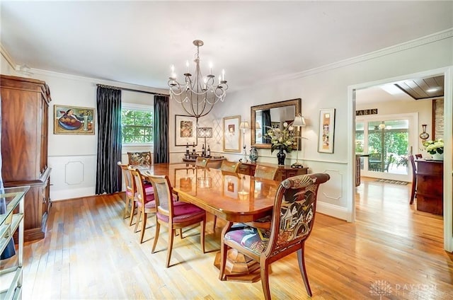 dining space featuring crown molding, a chandelier, a healthy amount of sunlight, and light hardwood / wood-style flooring