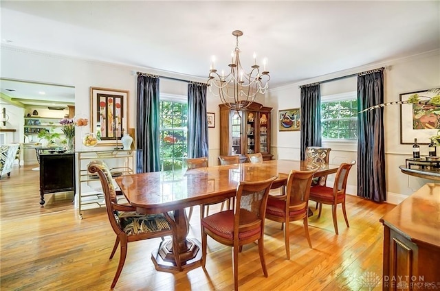 dining area with light wood-type flooring, a chandelier, crown molding, and a healthy amount of sunlight