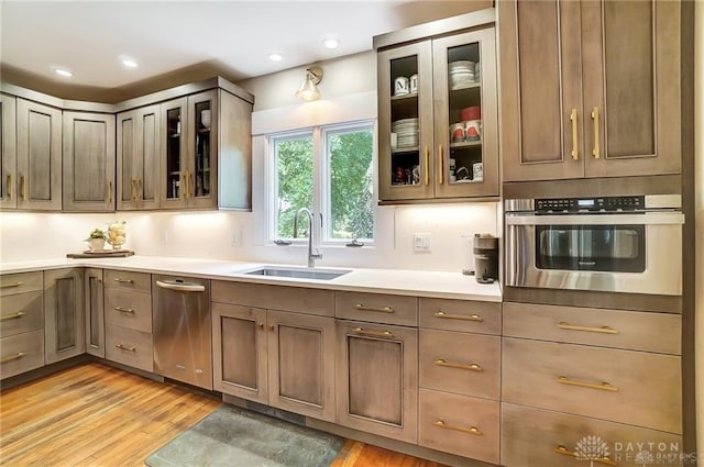 kitchen featuring sink, stainless steel oven, and light hardwood / wood-style flooring