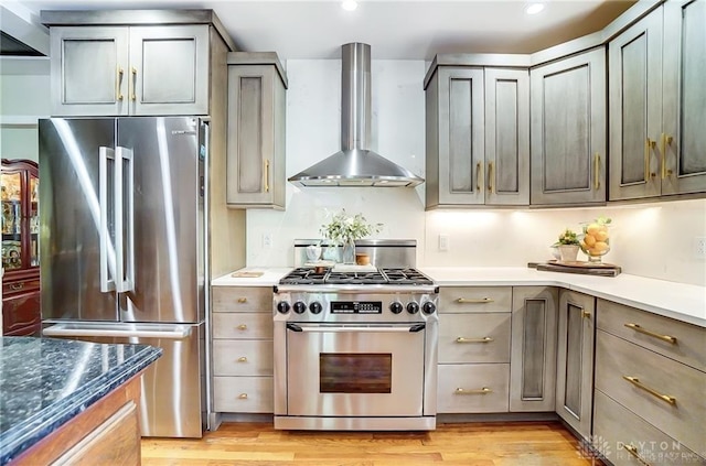 kitchen featuring appliances with stainless steel finishes, light hardwood / wood-style flooring, wall chimney exhaust hood, and gray cabinetry