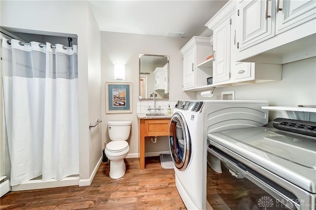 laundry area featuring sink, a baseboard radiator, washer and clothes dryer, and light hardwood / wood-style floors