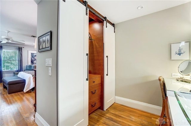 hallway featuring light wood-type flooring and a barn door