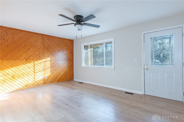 foyer entrance featuring wooden walls, ceiling fan, and light wood-type flooring