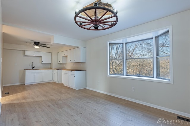 kitchen with sink, white cabinets, ceiling fan, and light hardwood / wood-style flooring