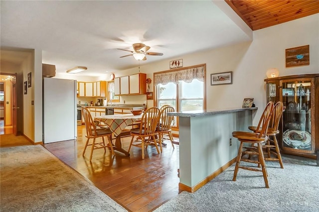 kitchen with hardwood / wood-style flooring, stainless steel fridge, ceiling fan, range, and kitchen peninsula