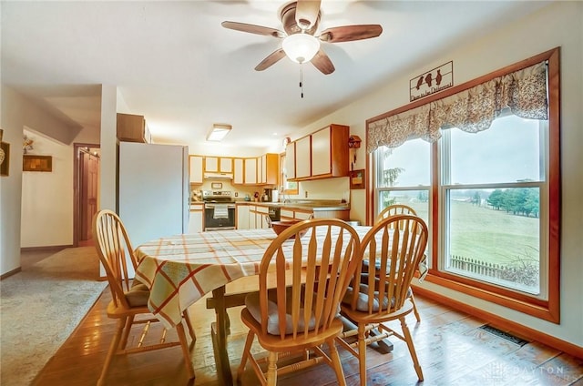 dining space featuring light carpet, sink, and ceiling fan