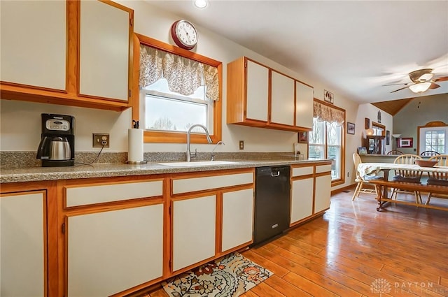 kitchen with sink, light hardwood / wood-style floors, white cabinets, and black dishwasher