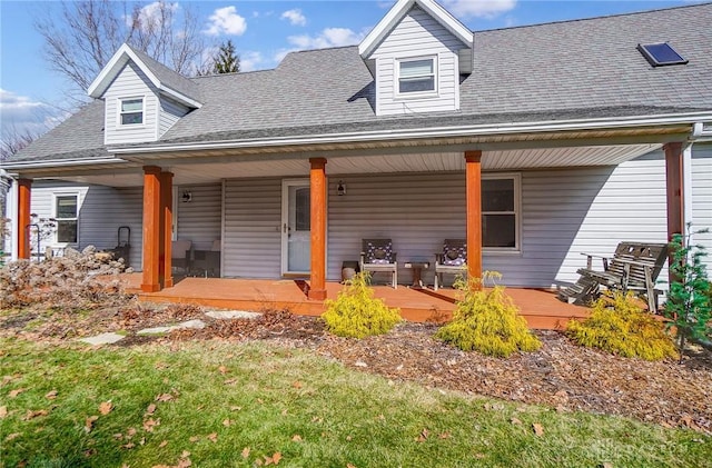 cape cod-style house featuring covered porch and a front lawn