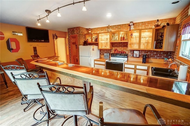 kitchen featuring butcher block countertops, sink, light hardwood / wood-style flooring, white refrigerator, and range with electric cooktop