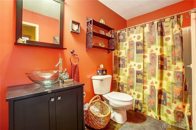 bathroom featuring a shower with curtain, vanity, toilet, and a textured ceiling