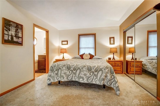 bedroom featuring light carpet, a closet, and ensuite bathroom