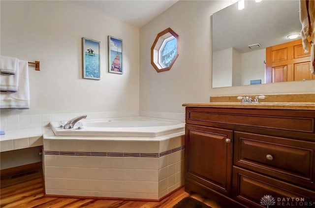 bathroom with tiled tub, vanity, and hardwood / wood-style flooring